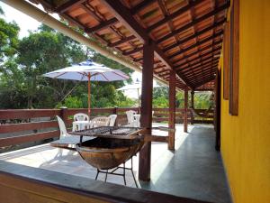 a patio with a table and chairs and an umbrella at Sobrado dos Pássaros in Arraial do Cabo