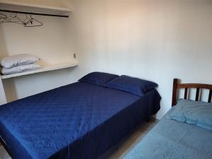 a bedroom with a blue bed and a shelf at Sobrado dos Pássaros in Arraial do Cabo