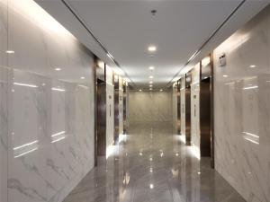 a hallway of a building with white marble walls at 免费接机/空中楼阁/水果西施夜市/热带雨林/RCA/无边泳池/近地铁Rama9 in Bangkok
