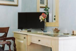 a tv on a desk with a vase of flowers at Casa Francy in Iglesias