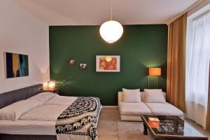 um quarto com uma parede verde com uma cama e um sofá em Vienna Palm Apartments em Viena