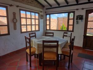 uma sala de jantar com mesa, cadeiras e janelas em El Rincon de Quevedo em Sáchica