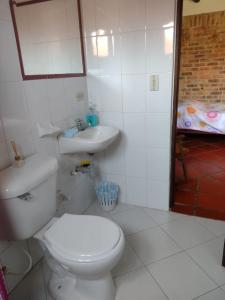 a white bathroom with a toilet and a sink at El Rincon de Quevedo in Sáchica