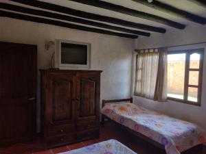 1 dormitorio con 1 cama, TV y vestidor en El Rincon de Quevedo, en Sáchica