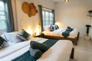 a bedroom with two beds and two windows at Baan Ragang : Cozy Entire House in Old Chiang Mai in Chiang Mai