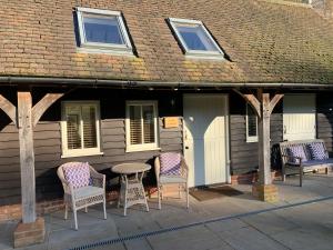 eine Terrasse mit Stühlen und einem Tisch vor einem Haus in der Unterkunft Stable Cottage in Dorking