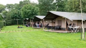 a tent with chairs and tables in a yard at Camping Emmen in Schoonebeek