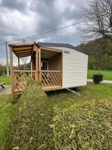 a small shed with a porch in the grass at Camping De la vallée in Durbuy