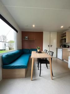 a living room with a blue couch and a table at Camping De la vallée in Durbuy