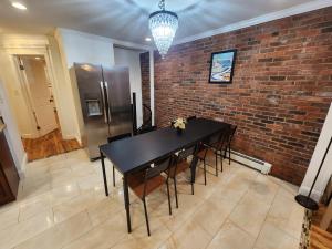 uma sala de jantar com uma mesa preta e uma parede de tijolos em Stylish 3 bed, minutes to NYC! em Jersey City