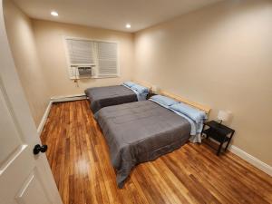 two beds in a room with wood floors at Stylish 3 bed, minutes to NYC! in Jersey City