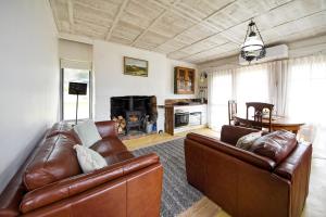 sala de estar con 2 sofás de cuero y chimenea en Devlin's Cottage, en Cape Bridgewater