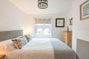 a white bedroom with a bed and a window at Samphire Cottage by Bloom Stays in Broadstairs