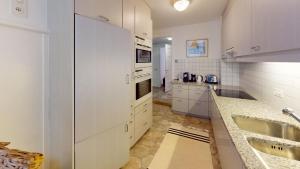 una cucina con armadi bianchi e lavandino di Apartment Chavallera 5 a Sankt Moritz