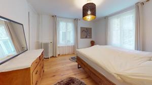 a bedroom with a large bed and two windows at Apartment Chavallera 5 in St. Moritz