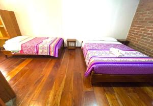 2 Betten in einem Zimmer mit Holzböden in der Unterkunft Exedra de Galeria Cafe. Mindo- Ecuador in Mindo