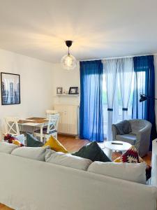 sala de estar con sofá blanco y cortinas azules en 2 Zimmer City Apartment mit Terrasse und Tiefgaragenstellplatz in Zentrum von Leipzig, en Leipzig