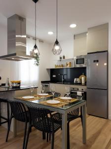 a kitchen with a table with chairs and a refrigerator at Somos Genius! Siéntete como en casa, en el corazón de Tarragona in Tarragona