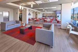 a lobby with couches and tables and a restaurant at City Express Junior by Marriott San Luis Potosi Carranza in San Luis Potosí