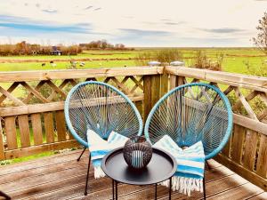 a table and two chairs on a deck with a field at Leichtes Gepäck in Pellworm