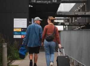 un homme et une femme marchant sur un trottoir avec bagages dans l'établissement Hotel GUESTapart, à Aarhus