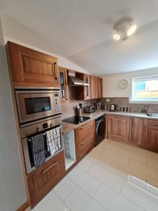 a kitchen with wooden cabinets and a microwave at Bruxie Holiday Cottages - River Cottage in Maud