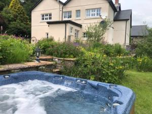a jacuzzi in a yard in front of a house at Onnen Fawr Farmhouse in Brecon