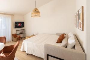 a white bedroom with a bed and a couch at Kolibri Apartment in Elsbethen