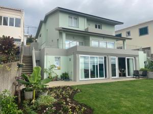 een groot huis met grote ramen en een tuin bij Myrtus - House with sea view and garden in Funchal