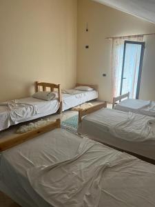 a room with three beds and a window at Bujtina Merturi in Aprip