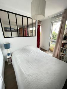 een slaapkamer met een wit bed en een grote spiegel bij Studio récent Cosy - Ploemeur in Ploemeur