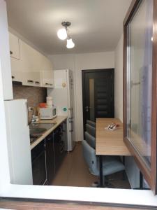 a small kitchen with a table and a white refrigerator at Stefania Apartment Sibiu in Şelimbăr +20 photos