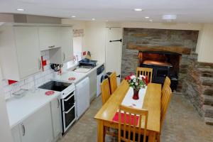 cocina con mesa, sillas y pared de piedra en The Ash Cottage, en Brecon