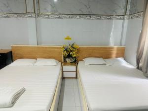 2 camas en una habitación con sábanas blancas y flores en Nhà nghỉ Trung Hiếu 1, en Bình Thủy