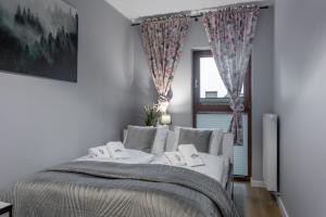 een slaapkamer met een wit bed en een raam bij Apartament A19 Green Park Resort -basen ,sauny ,siłownia ,jacuzzi in Szklarska Poręba