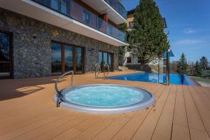 einen Whirlpool auf einer Terrasse neben einem Gebäude in der Unterkunft Apartament A19 Green Park Resort -basen ,sauny ,siłownia ,jacuzzi in Szklarska Poręba