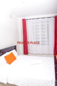 a bedroom with a white bed and red curtains at Pearl's Place in Meru