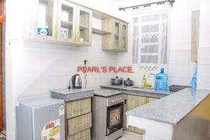 uma cozinha com um lavatório e um fogão forno superior em Pearl's Place em Meru