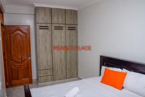 1 dormitorio con cama y armario de madera en Pearl's Place, en Meru