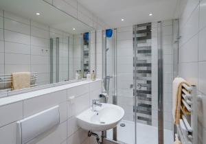 ein weißes Bad mit einem Waschbecken und einer Dusche in der Unterkunft di Holting Hüs in Westerland