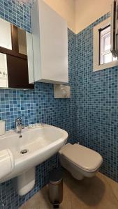 a blue tiled bathroom with a sink and a toilet at Elly’s House in Bari