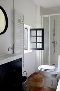 a white bathroom with a toilet and a sink at Maison - Les Traversières in Eymet