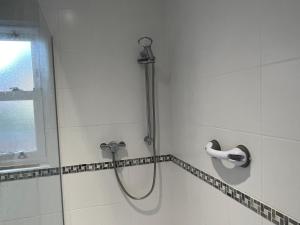a shower with a shower head in a bathroom at Cosy Hillside Annex in Stanwick