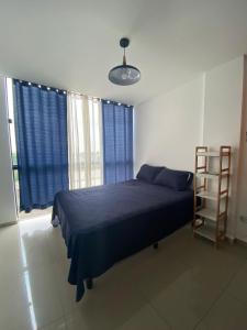 a bedroom with a bed with blue sheets and windows at Mono ambiente Cond Barak 1 in Santa Cruz de la Sierra