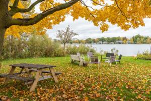 a picnic table and chairs under a tree next to a lake at Campau Lake Sunshine cottage in Cascade