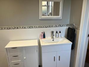 a bathroom with a white sink and a mirror at Cosy Hillside Annex in Stanwick