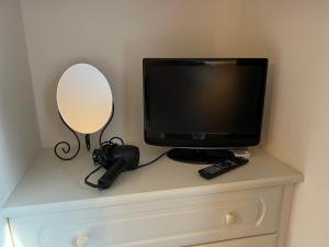 um monitor de computador sentado em cima de uma cómoda com um espelho em Cosy Hillside Annex em Stanwick