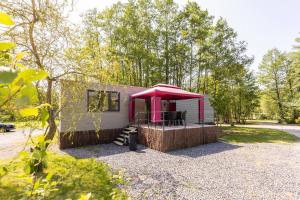 a small house with a red awning in a yard at Tinyhouses - Domain "La vallée des Prés" in Bande