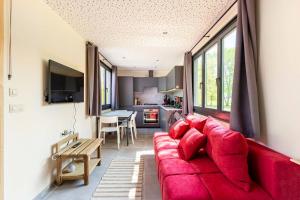 a living room with a red couch and a kitchen at Tinyhouses - Domain "La vallée des Prés" in Bande