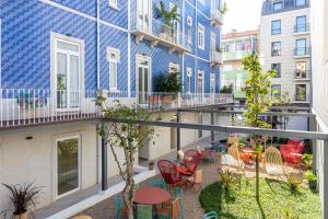 Apartment-Balkon mit einem blauen Gebäude sowie Tischen und Stühlen in der Unterkunft Haws Lisboa in Lissabon